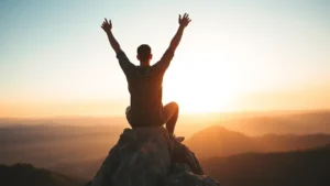 Person sitting on mountain peak at sunrise, arms raised in triumph, overlooking vast landscape, feeling accomplished and energized, natural lighting, peaceful expression