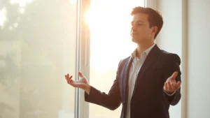 Professional person in morning sunlight by window practicing mindfulness meditation, calm focused expression, natural light creating peaceful atmosphere, no text visible